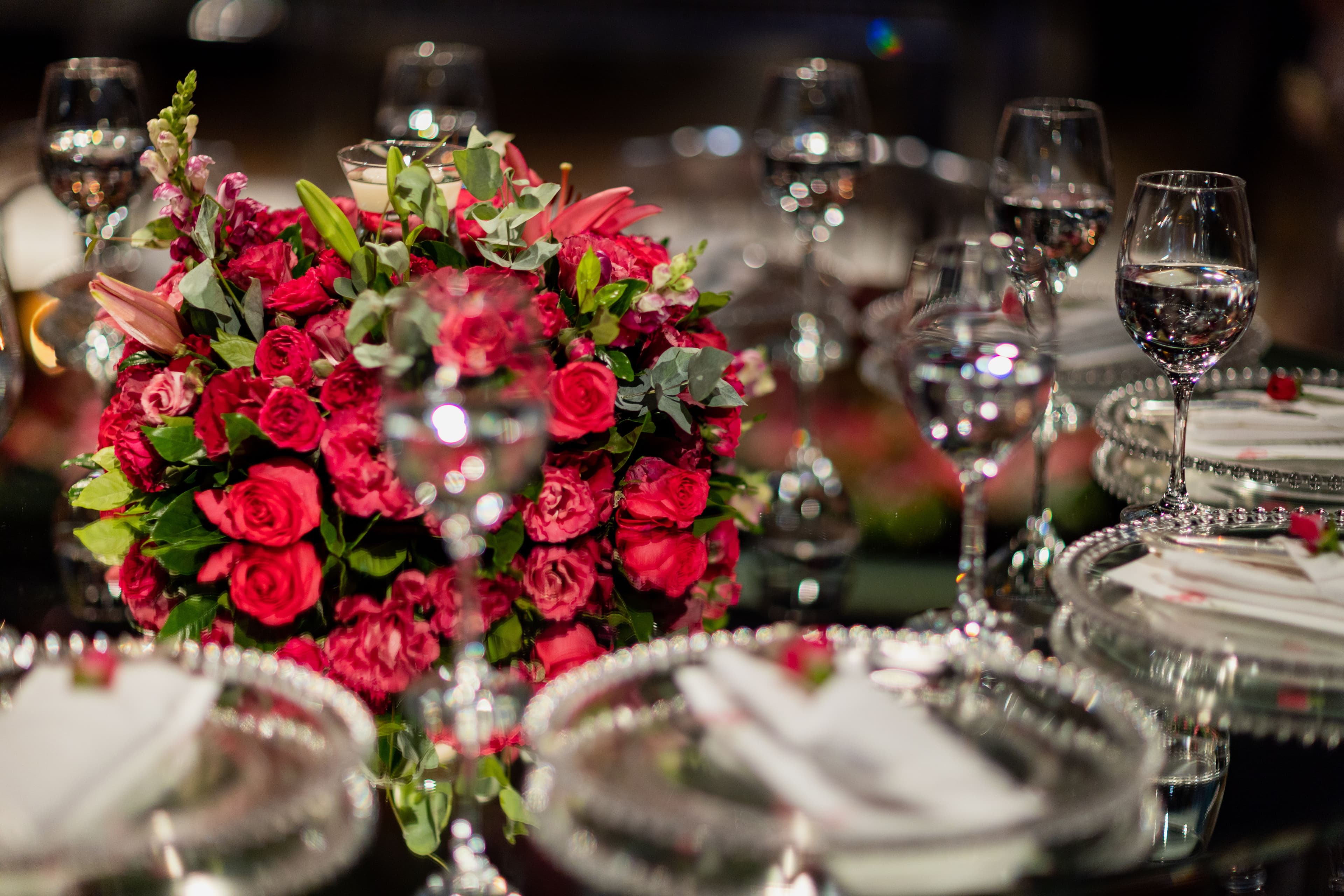 Luxurious wedding table setting with red roses and crystal glassware